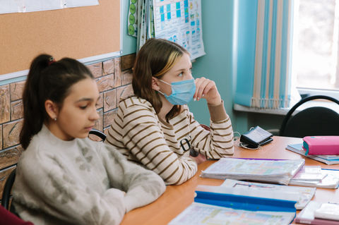 Students in a lesson with Interclass materials, one wearing a protective mask