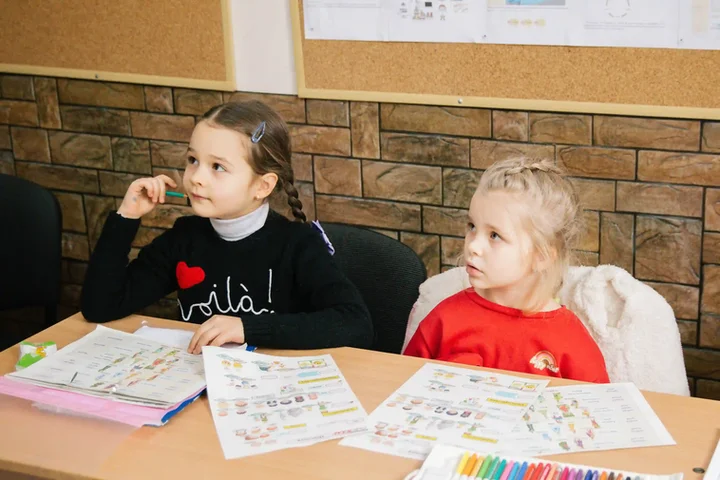 Two girls work with learning maps and coloured pencils