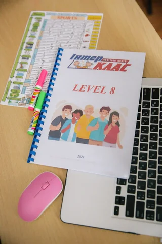 An Interclass Level 8 textbook and teaching materials beside a laptop