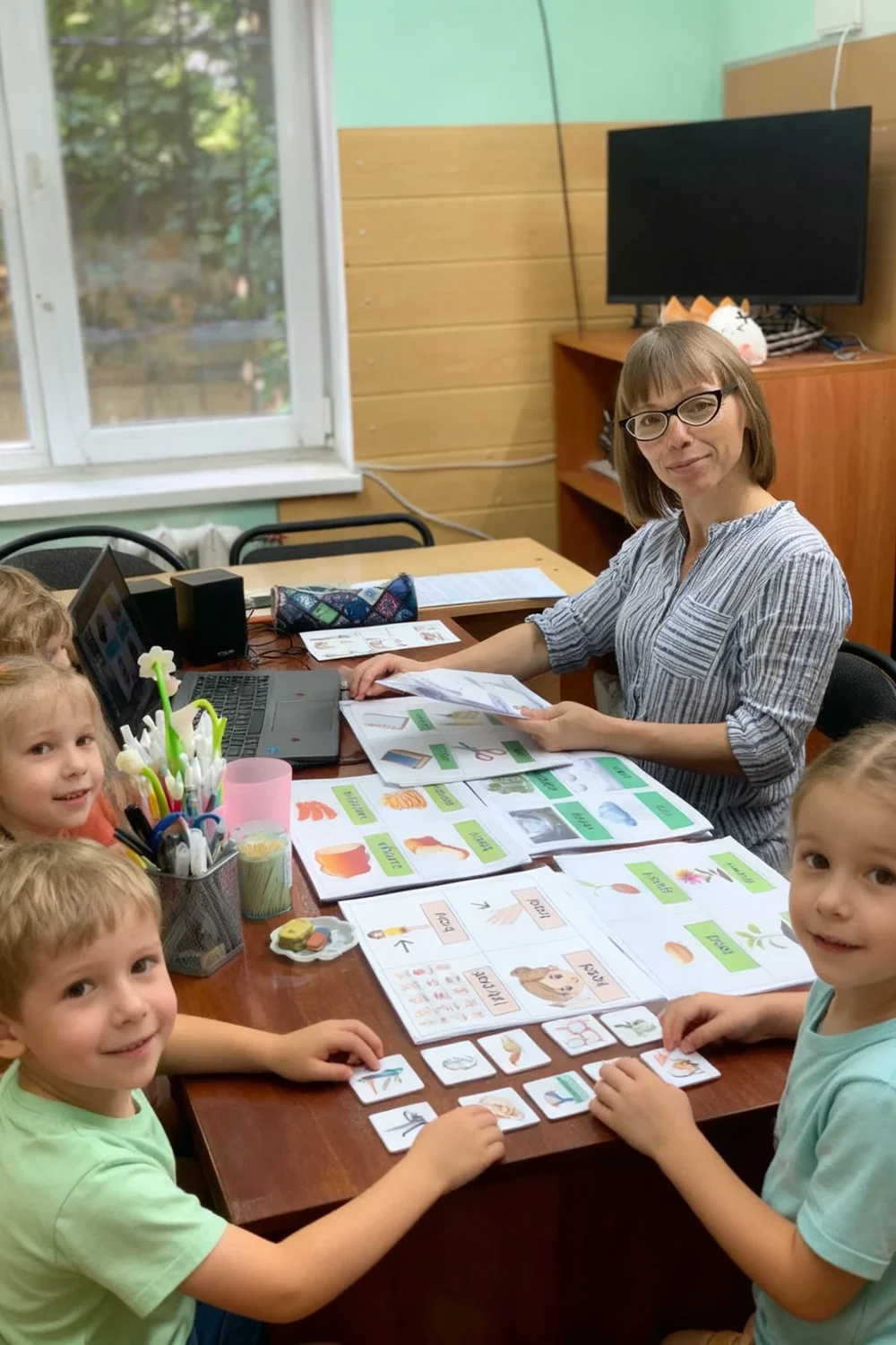A preschool lesson: a teacher and children work with Interclass maps and pictograms